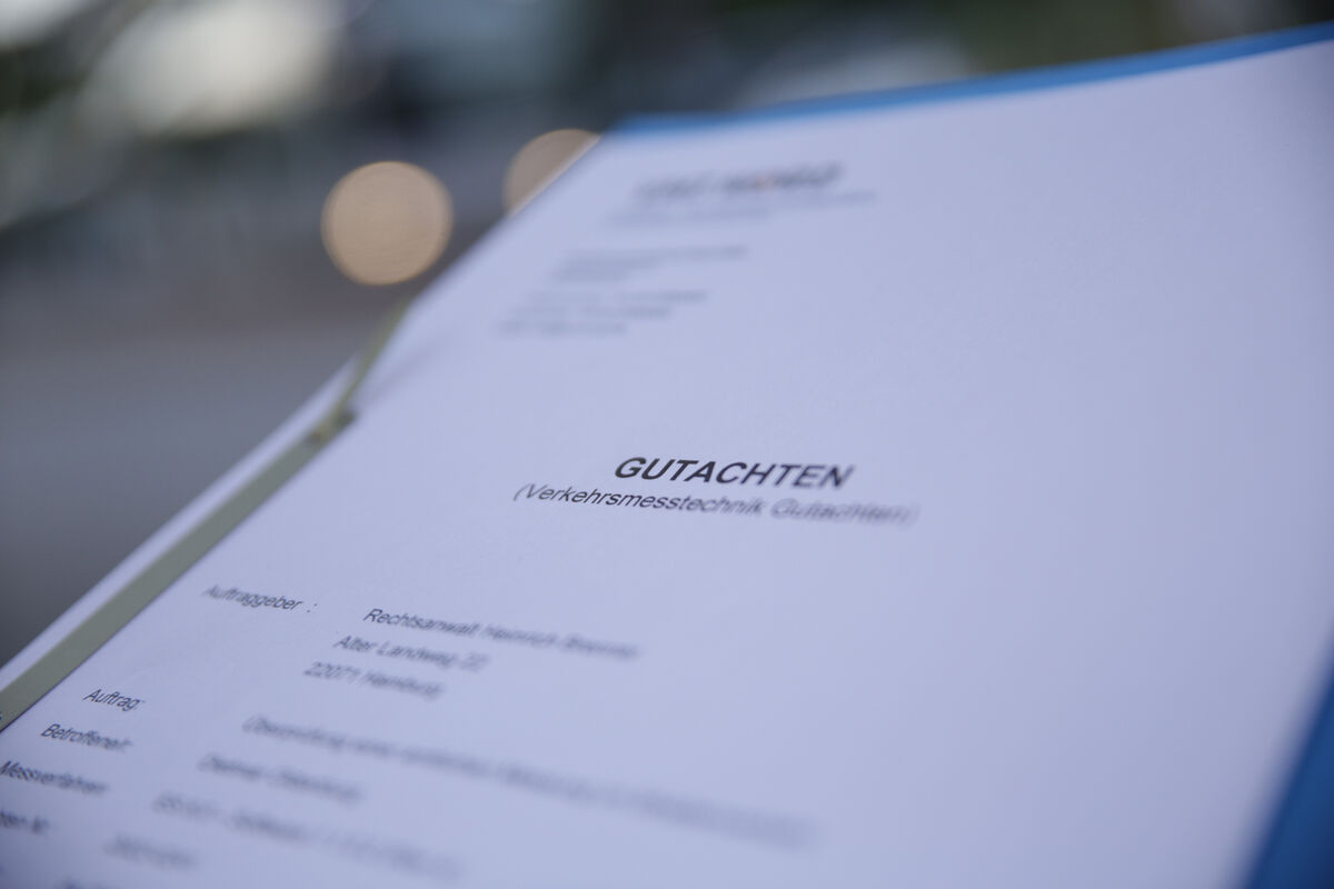 Sachverständiger prüft am Schreibtisch eine Bußgeldakte mit Messprotokoll und Beweisfotos einer Geschwindigkeitsmessung